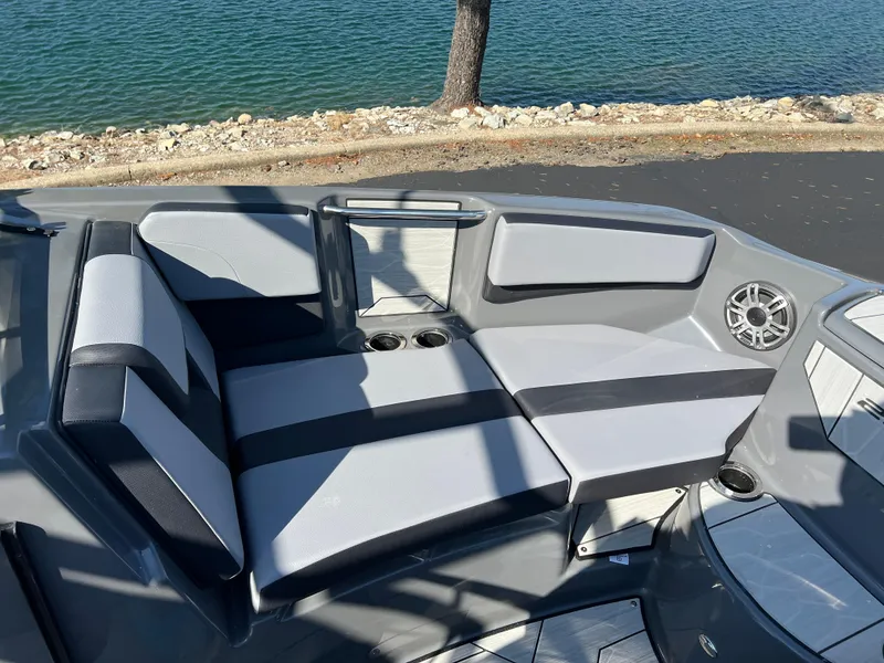 Slide: The Image of 2025 Yamaha Boats 222XD interior seating with cup holders, near a scenic waterfront. - 17