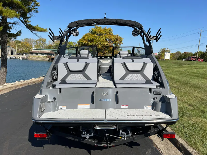 Slide: The Image of 2025 Yamaha Boats 222XD, rear view, parked by a lakeside on a sunny day. - 6