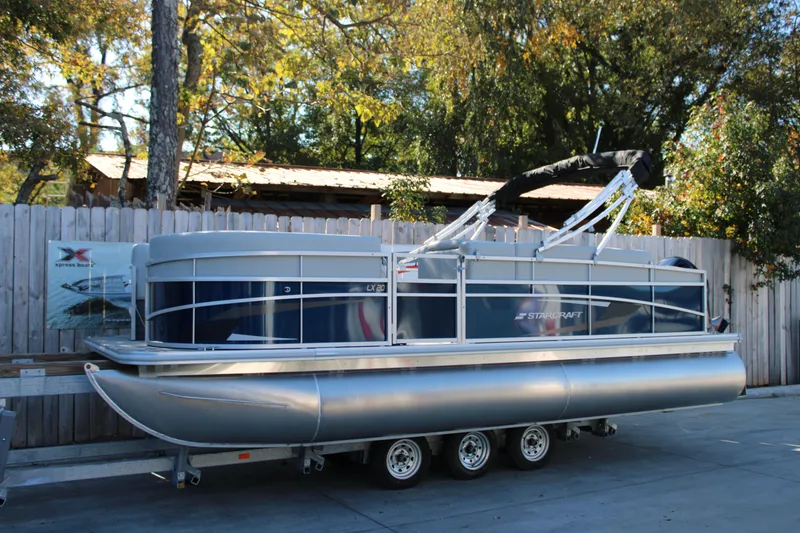 The Image of 2025 Starcraft LX 20 CB pontoon boat parked outdoors. - 0