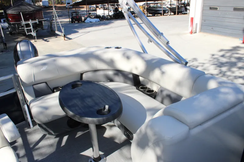 Slide: The Image of 2025 Starcraft LX 20 CB boat interior with seating and table, docked outdoors. - 12