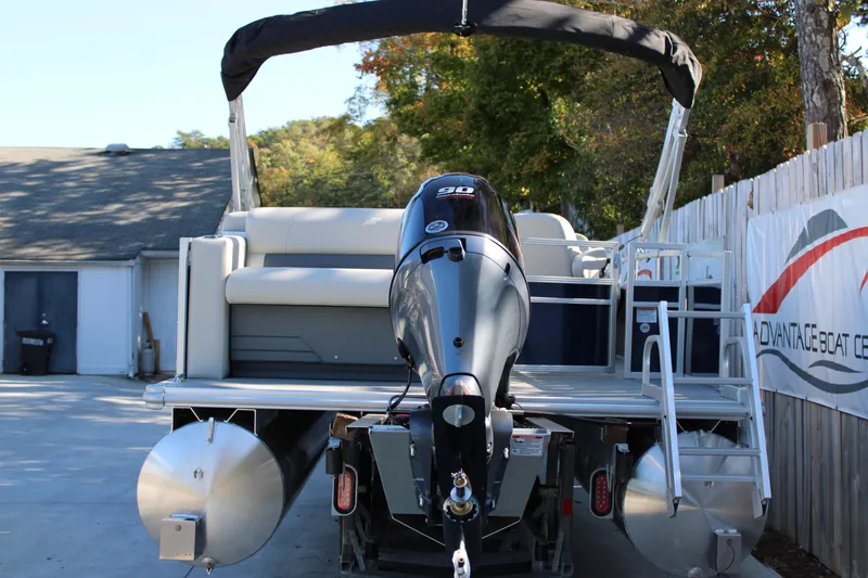 Slide: The Image of 2025 Starcraft LX 20 CB pontoon boat with outboard motor, parked on trailer. - 14