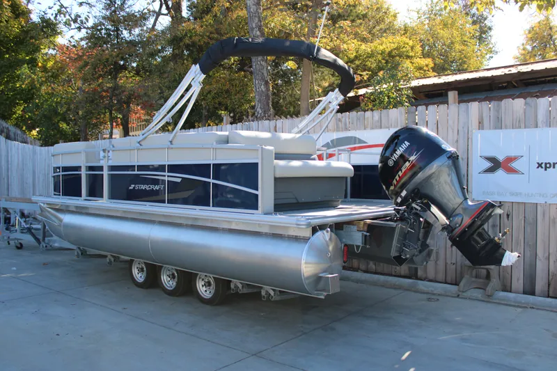 Slide: The Image of 2025 Starcraft LX 20 CB pontoon boat with Yamaha outboard motor, parked on trailer. - 15