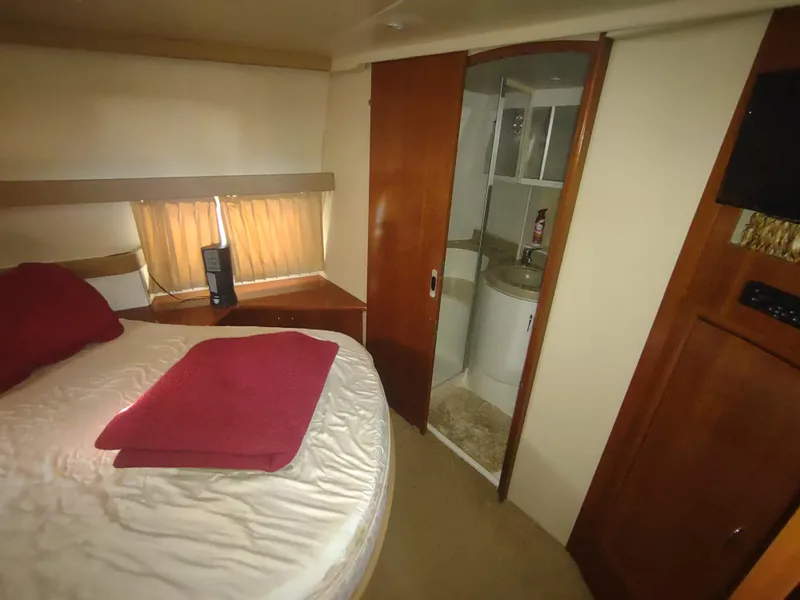 Slide: The Image of 2004 Carver 366 Motor Yacht bedroom with ensuite bathroom, featuring cozy bed and wooden accents. - 27