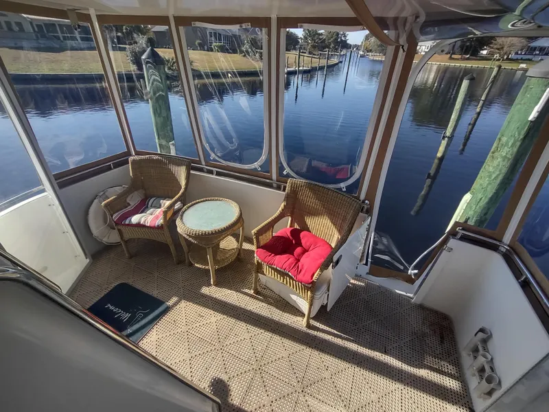 Slide: The Image of 2004 Carver 366 Motor Yacht interior with wicker chairs and table, overlooking serene waterway. - 46