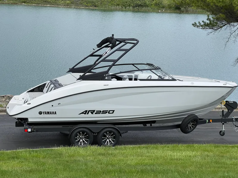 The Image of 2025 Yamaha AR250 boat on trailer by a lake, showcasing sleek design and modern features. - 1