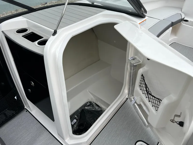Slide: The Image of 2025 Yamaha AR250 boat storage compartment with open door and cup holders. - 15