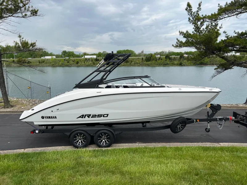Slide: The Image of 2025 Yamaha Boats AR250 on trailer by a lakeside road. - 3