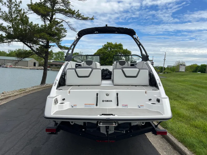 Slide: The Image of 2025 Yamaha Boats AR250 on trailer, rear view by lakeside, under blue sky. - 5