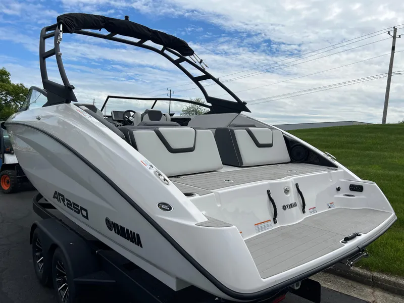 Slide: The Image of 2025 Yamaha Boats AR250, sleek white design, rear view, parked outdoors. - 6