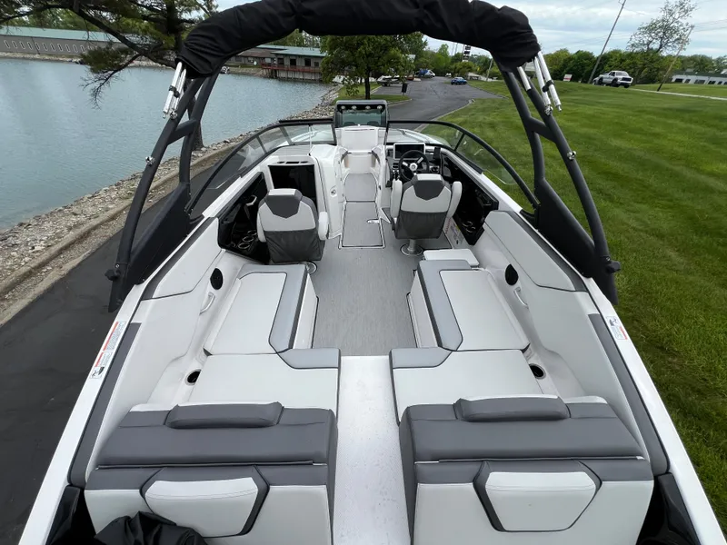 Slide: The Image of 2025 Yamaha Boats AR250 interior, spacious seating, sleek design, docked by a serene lake. - 8