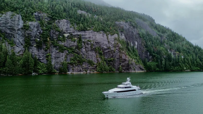 Slide: The Image of Delta Motoryacht cruising near lush, rocky cliffs, 2001 model. - 10