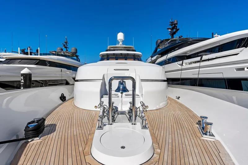 Slide: The Image of Delta 124 Motoryacht 2001, sleek deck view with polished wood and bell, docked between yachts. - 20
