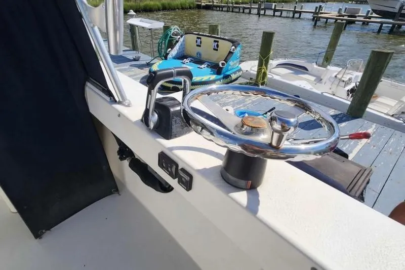 Slide: The Image of Steering wheel of 2018 Judge 27 Chesapeake XL boat docked by the water. - 18