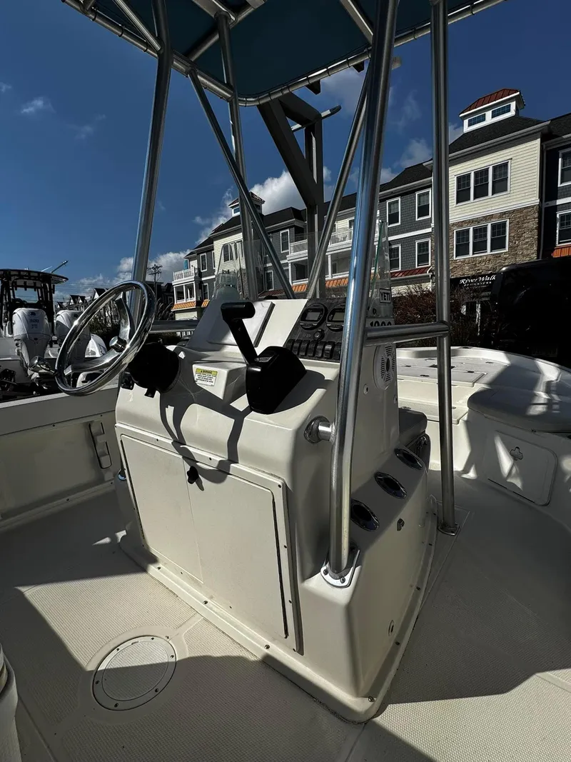 Slide: The Image of 2014 Sailfish 1900 BB Bay Boat interior with steering console, docked near waterfront buildings. - 4