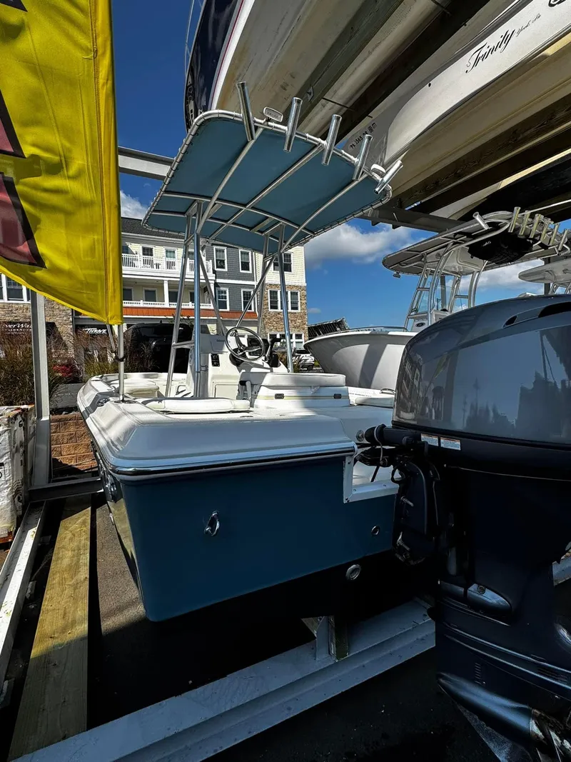 Slide: The Image of 2014 Sailfish 1900 BB Bay Boat with outboard motor, docked under a canopy. - 7