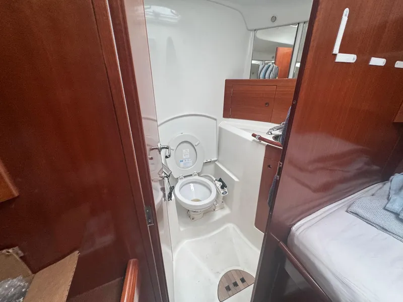 Slide: The Image of Beneteau First 47.7 yacht bathroom interior, 2004 model, featuring wooden cabinetry and compact design. - 29