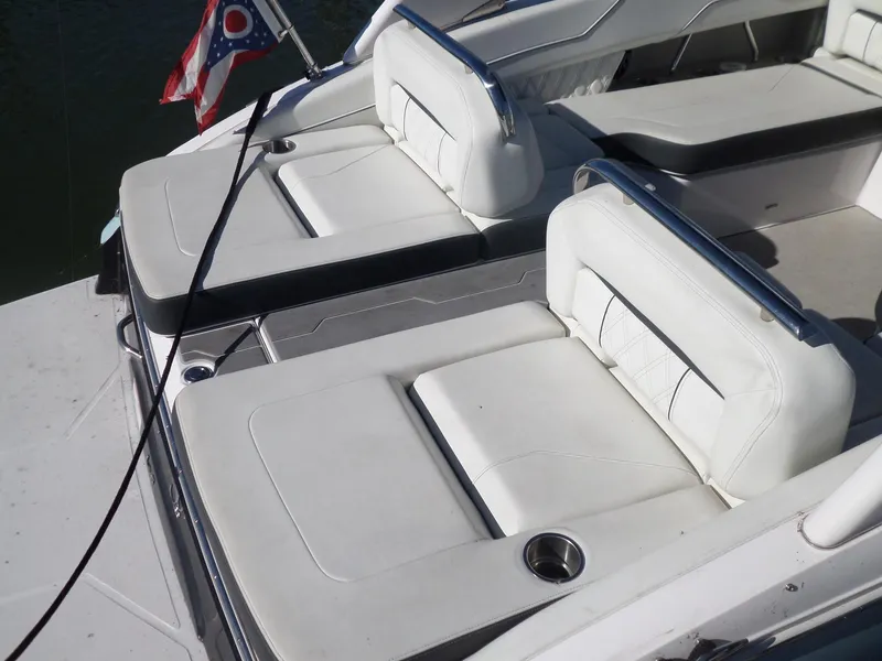Slide: The Image of 2020 Regal LS6 boat with white leather seating and cup holders, docked near water. - 10