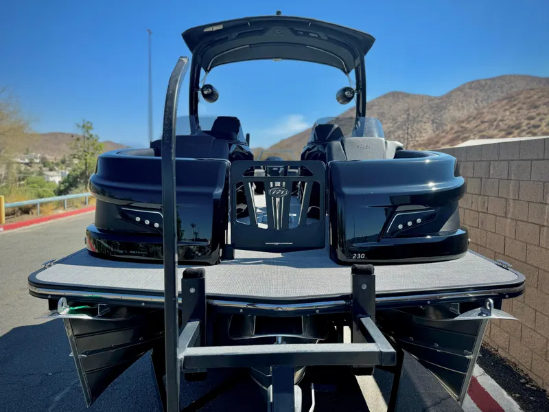 Slide: The Image of 2024 Manitou 23 XT RFXW pontoon boat, rear view, parked on a sunny day. - 2
