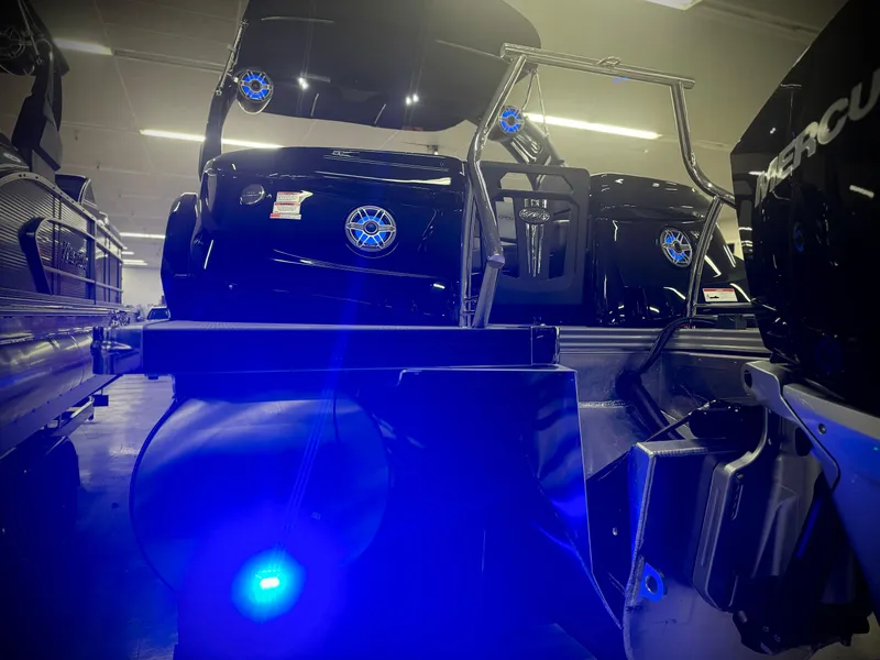 Slide: The Image of 2024 Manitou 23 XT RFXW boat with blue LED lights in showroom. - 29