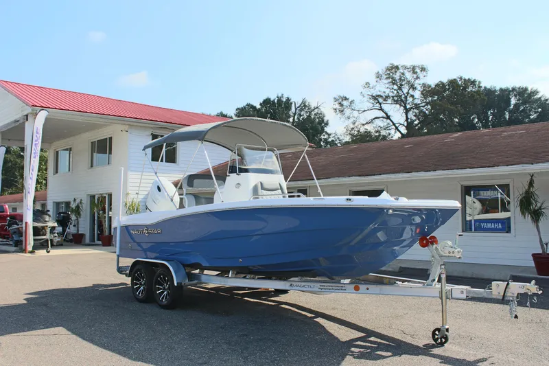 Slide: The Image of 2025 NauticStar 211 Hybrid boat on trailer outside dealership. - 4