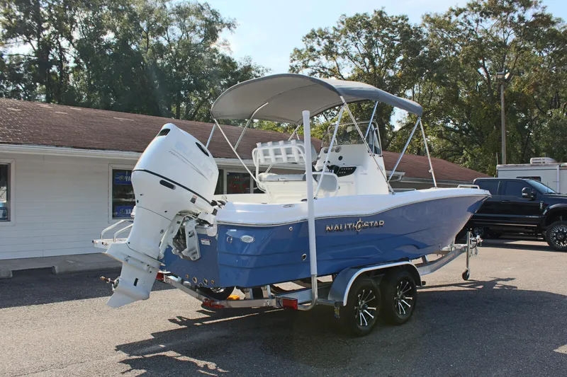 Slide: The Image of 2025 NauticStar 211 Hybrid boat on trailer, blue hull, parked outdoors. - 7
