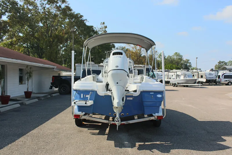 Slide: The Image of 2025 NauticStar 211 Hybrid boat with outboard motor, parked in a lot. - 8