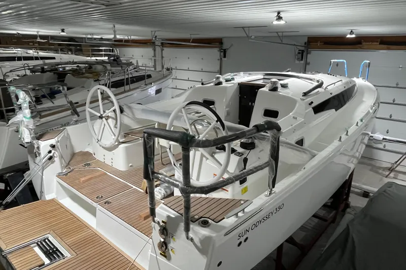 The Image of 2026 Jeanneau Sun Odyssey 350 sailboat in indoor storage, showcasing dual steering wheels. - 0