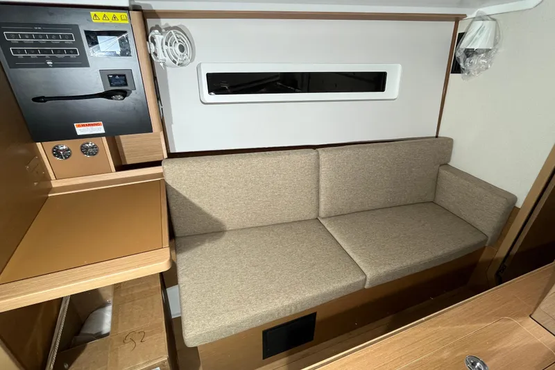 Slide: The Image of 2026 Jeanneau Sun Odyssey 350 interior with beige sofa and control panel. - 5