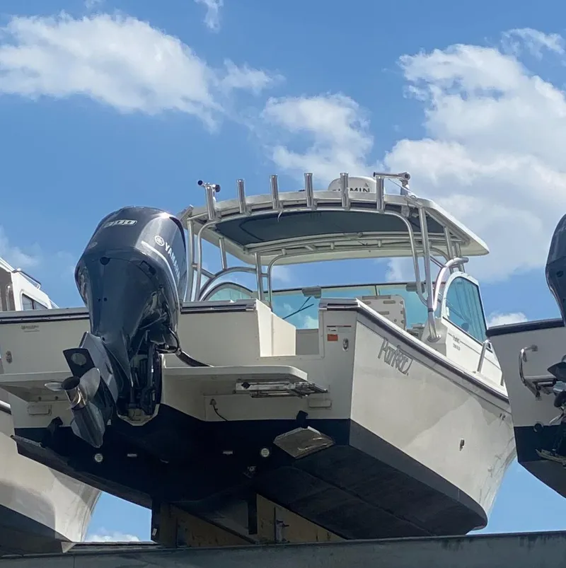Slide: The Image of 2015 Parker 2510 XLD boat with outboard motor, docked under a blue sky. - 4