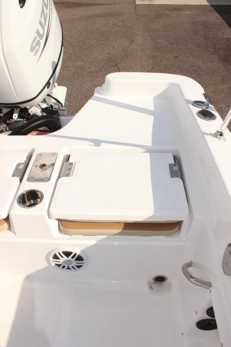 Slide: The Image of 2025 NauticStar 231 Hybrid boat deck with Suzuki engine, featuring storage and cup holders. - 11