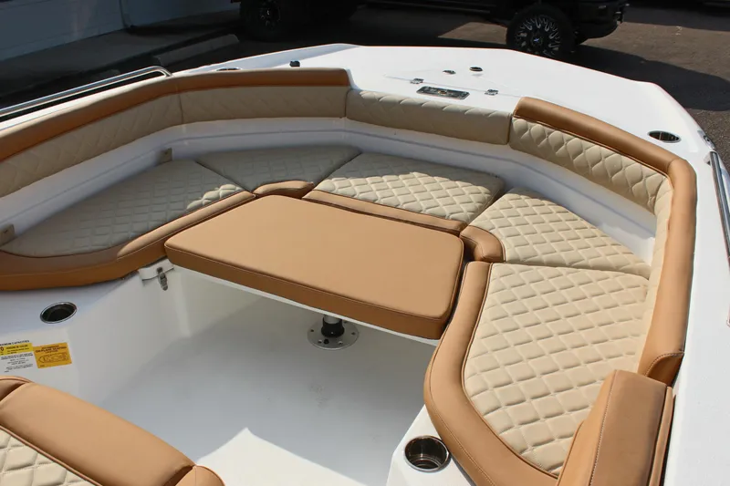 Slide: The Image of 2025 NauticStar 231 Hybrid boat interior with tan cushioned seating and table. - 22