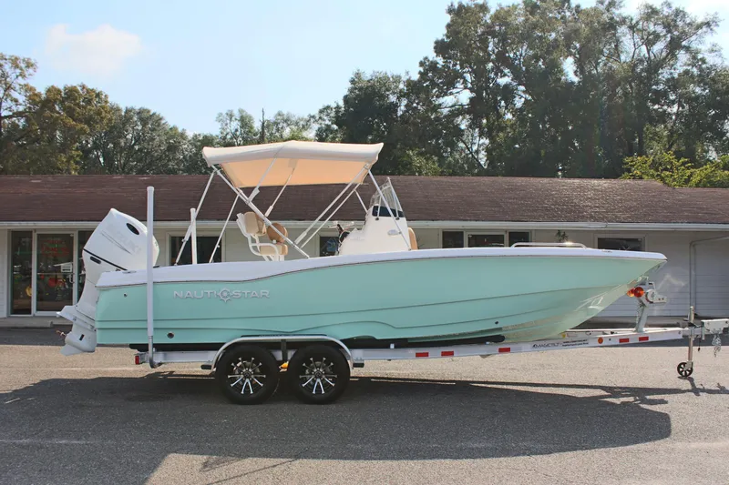 Slide: The Image of 2025 NauticStar 231 Hybrid boat on trailer, parked outdoors. - 6
