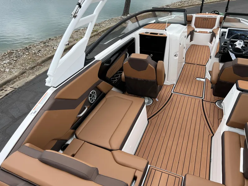 Slide: The Image of 2025 Yamaha Boats 252S interior with brown seating and sleek design by the water. - 11