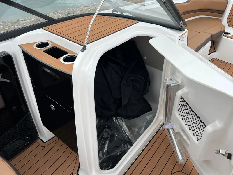 Slide: The Image of 2025 Yamaha Boats 252S interior storage compartment with open door and cup holders. - 16