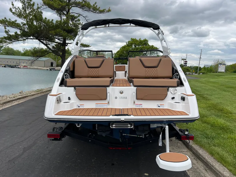Slide: The Image of 2025 Yamaha Boats 252S with tan seating, docked near a grassy shoreline. - 5