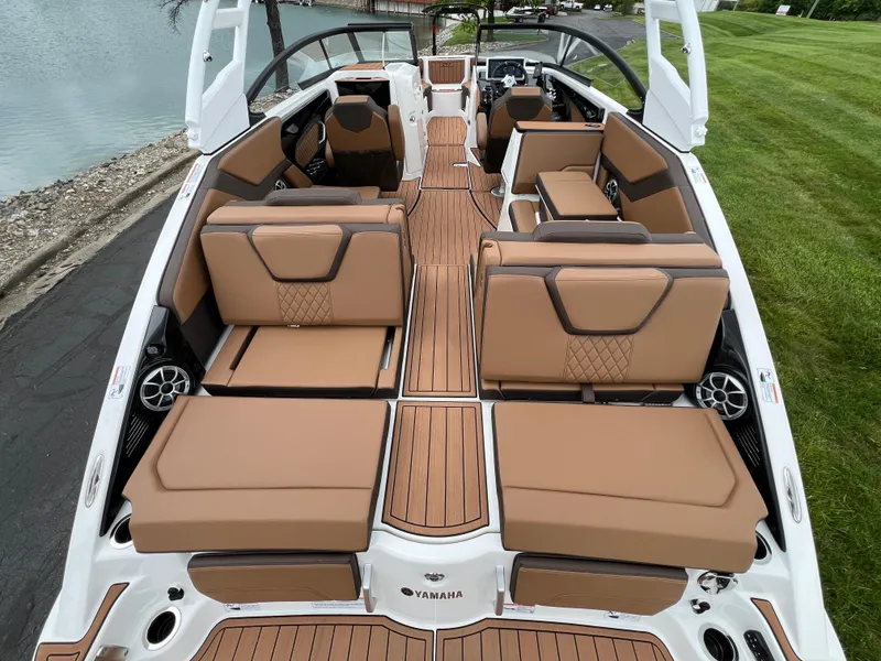 Slide: The Image of 2025 Yamaha Boats 252S interior with tan seating and sleek design by the water. - 8