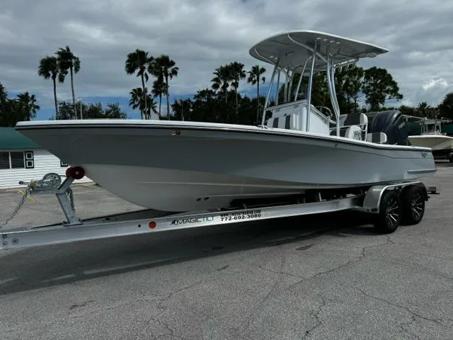 Slide: The Image of 2025 BlackJack 224 boat on trailer, parked outdoors with palm trees in background. - 1