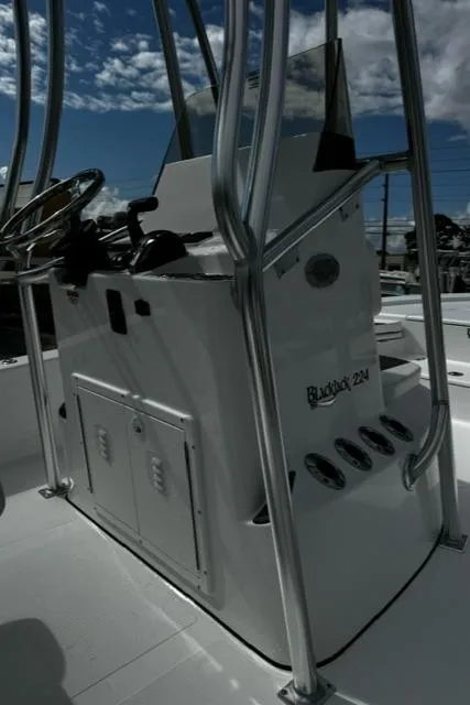 Slide: The Image of 2025 BlackJack 224 boat console with steering wheel and controls under a blue sky. - 12