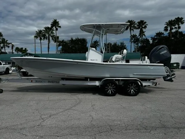Slide: The Image of 2025 BlackJack 224 boat on trailer, parked outdoors under cloudy sky. - 2