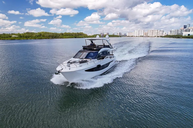 Slide: The Image of Galeon 640 Fly 2020 yacht cruising on a sunny day, cityscape in background. - 0