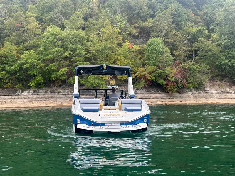 Slide: The Image of 2024 Nautique Super Air Nautique G25 Paragon on a serene lake with lush forest backdrop. - 3