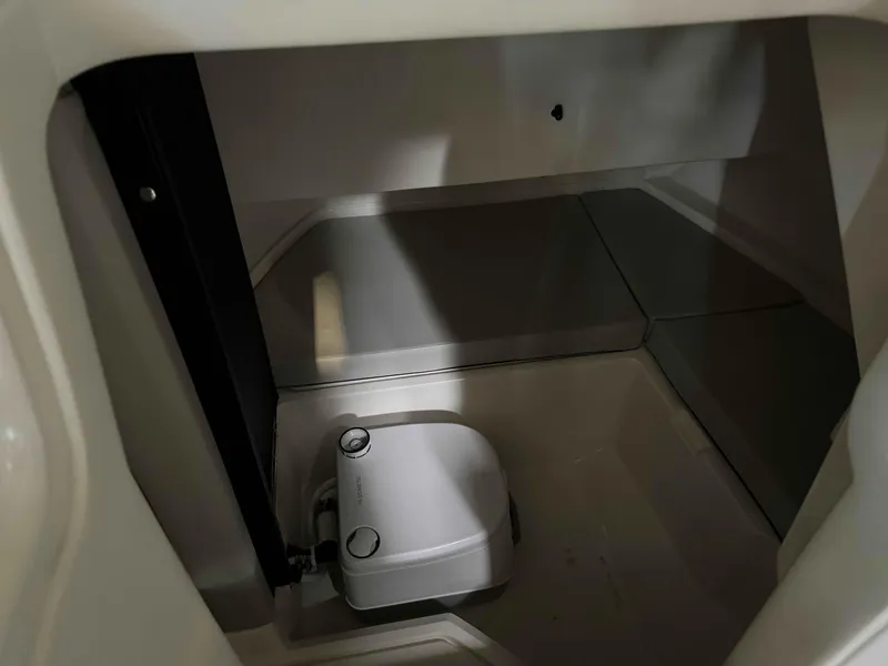 Slide: The Image of 2023 Sea Ray 250SDX interior storage compartment with portable toilet. - 7