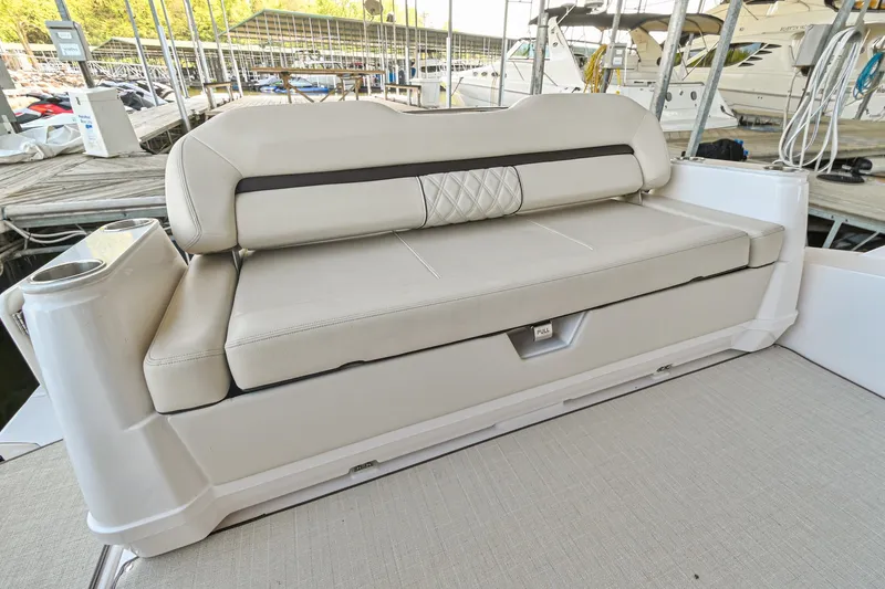 Slide: The Image of 2021 Regal 36 Grande Coupe boat seating area with beige upholstery at a marina. - 16