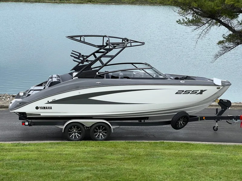Slide: The Image of 2025 Yamaha Boats 255XE on trailer by a lake, showcasing sleek design and modern features. - 1