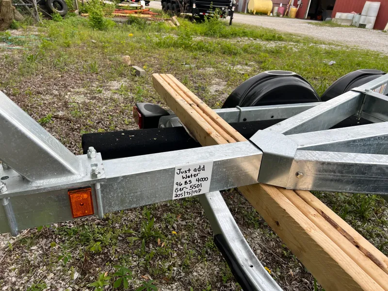 Slide: The Image of Trailer for 2025 Yamaha Boats 255XE, parked on gravel with wooden planks. - 10