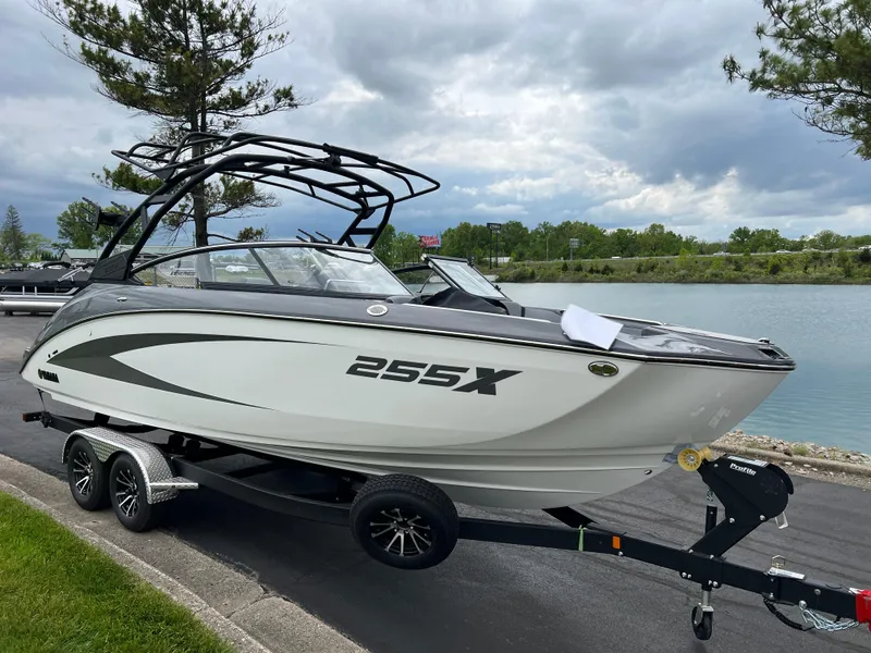 Slide: The Image of 2025 Yamaha Boats 255XE on trailer by a scenic lakeside. - 2