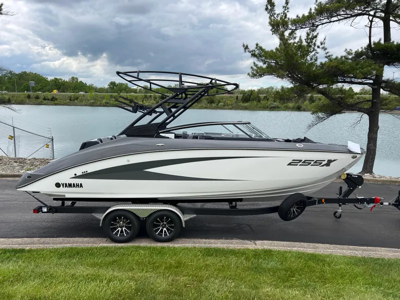 Slide: The Image of 2025 Yamaha Boats 255XE on trailer by a lake, under cloudy sky. - 3