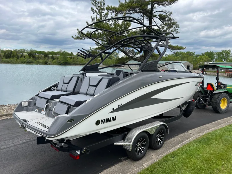 Slide: The Image of 2025 Yamaha Boats 255XE on trailer by a lake, showcasing sleek design and modern features. - 4