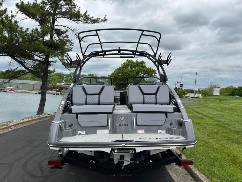 Slide: The Image of 2025 Yamaha Boats 255XE, rear view, parked near a lake under cloudy skies. - 5