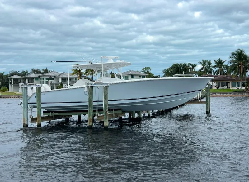 Slide: The Image of 2021 Jupiter 38 HFS boat docked on lift, waterfront homes in background. - 20